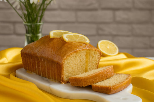 Soft, golden chamomile tea cake topped with a light honey glaze and lemon slices flowers, served on a stone plate kept over yellow satin cloth.