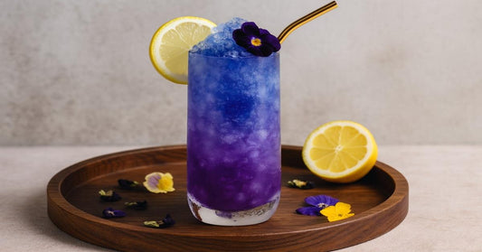 Butterfly pea flower iced tea mocktail with lemon, showcasing vibrant blue and purple hues, served in a tall glass with edible flowers — caffeine-free herbal drink for focus and hydration.